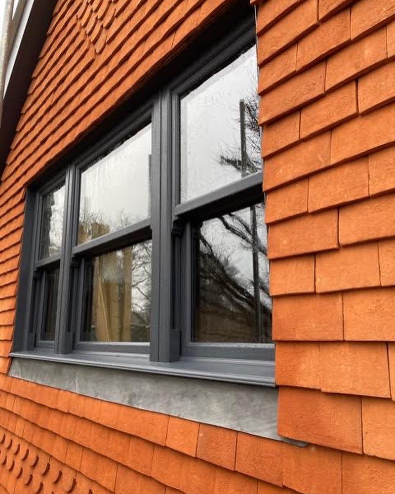 A side view of a house featuring a window framed by vibrant orange siding, showcasing a bright and cheerful exterior.