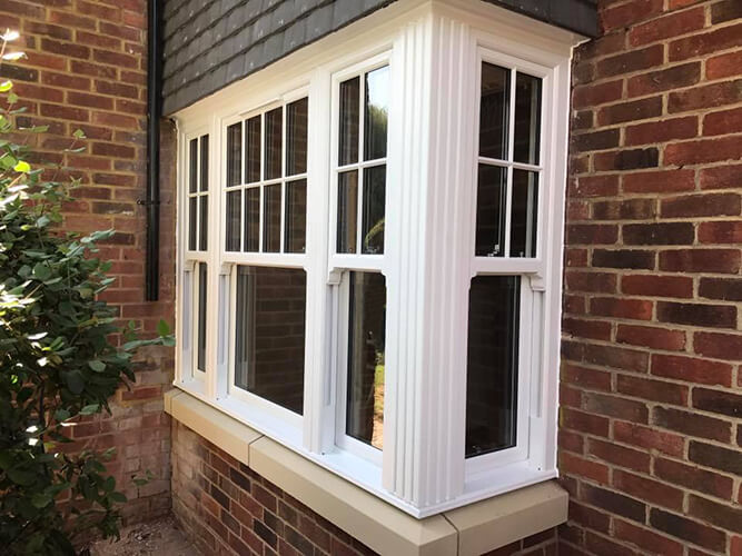 A white window framed by a brick wall and brick trim, showcasing a classic architectural design.